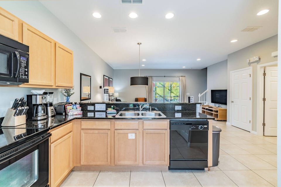 This spacious kitchen, with its stylish black appliances and warm wooden cabinetry, invites you to enjoy culinary adventures. Bright natural light fills the open layout, making it perfect for gathering and sharing meals together.