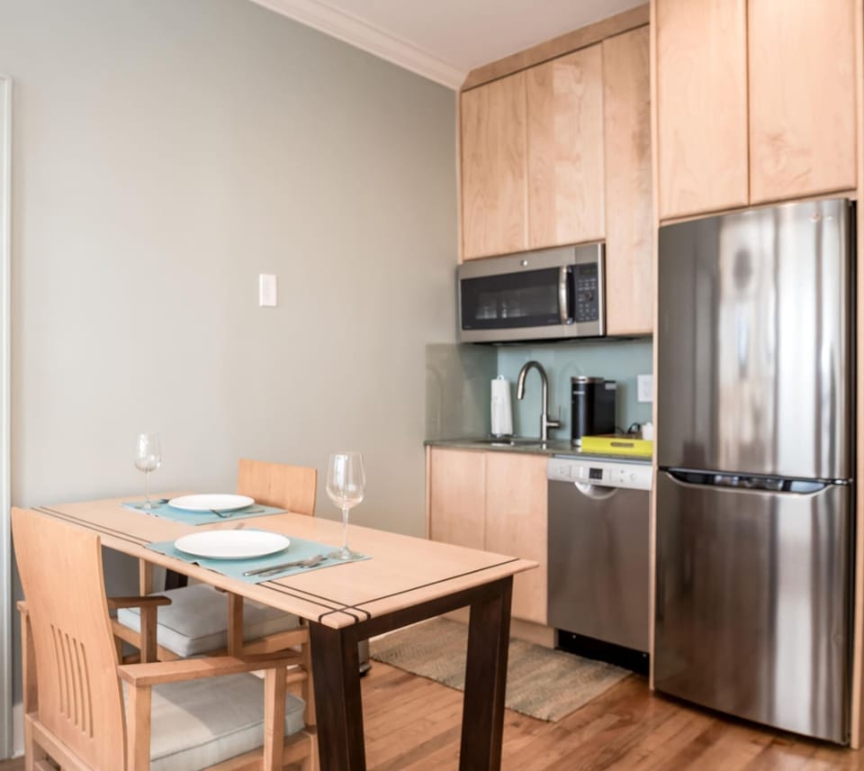 Dining area, Kitchenette with microwave, fridge, Keurig coffee maker, glasses, plates, and cutlery
