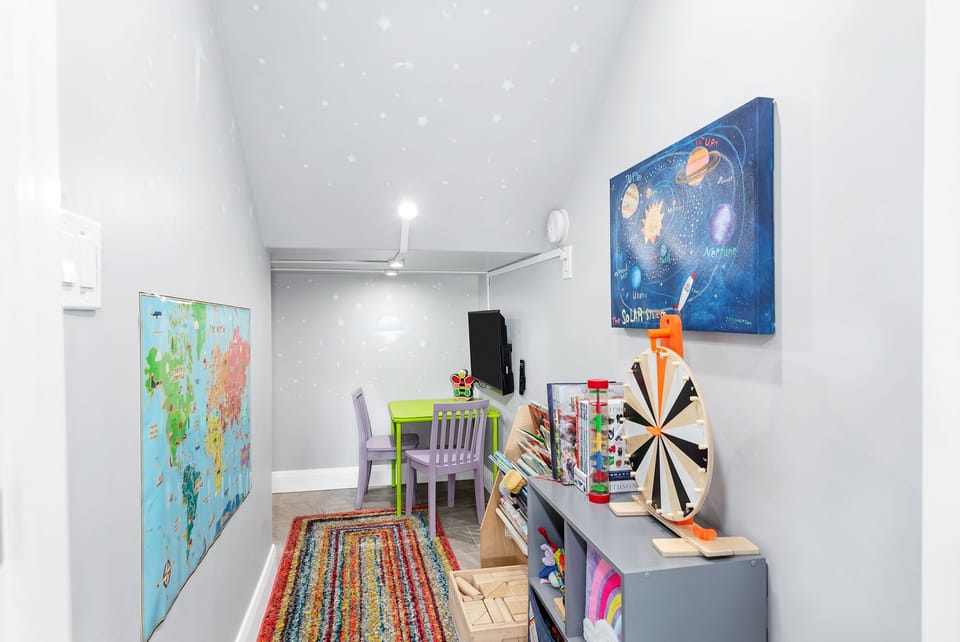 Kids' playroom with smart TV, a table, games and books