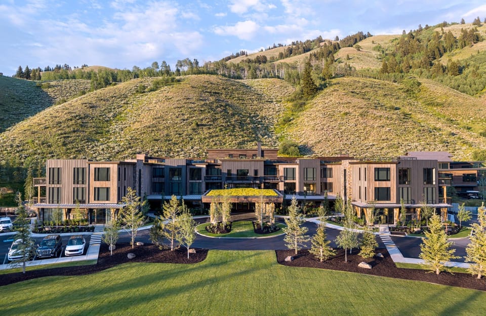 Wood-and-stone lodge exterior framed by the Teton peaks — your gateway to 1,000 acres of private Wyoming wilderness