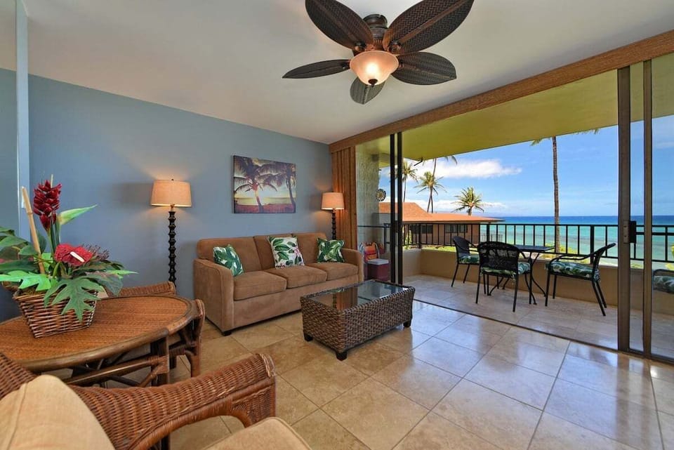 Living room with wicker furniture, tropical décor, and balcony ocean view.