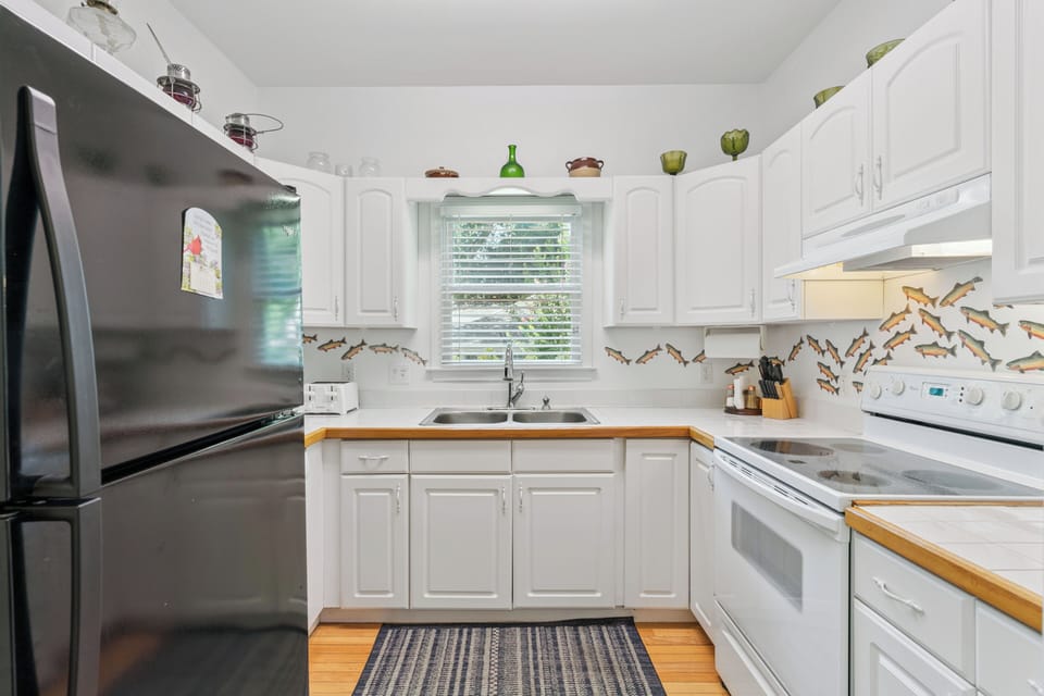 Cook up your favorite meals in this fully equipped kitchen, complete with modern appliances, ample counter space, and charming coastal-themed backsplash details.