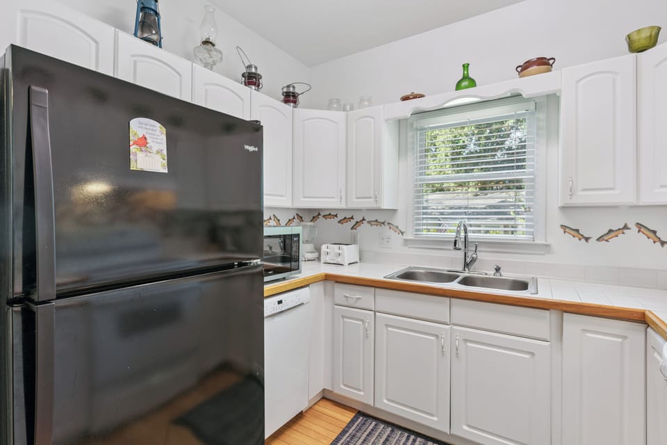 Your fully-equipped kitchen features bright white cabinetry, warm wood countertops, and charming coastal details that make meal prep feel like part of your vacation.