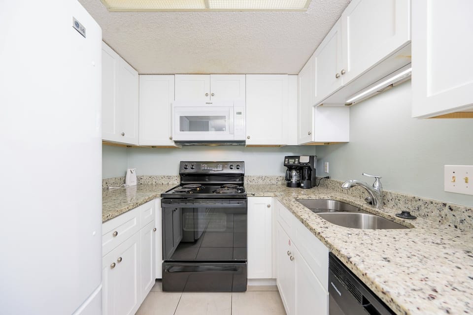 This kitchen features sleek black appliances, granite countertops, and coffee makers for your convenience