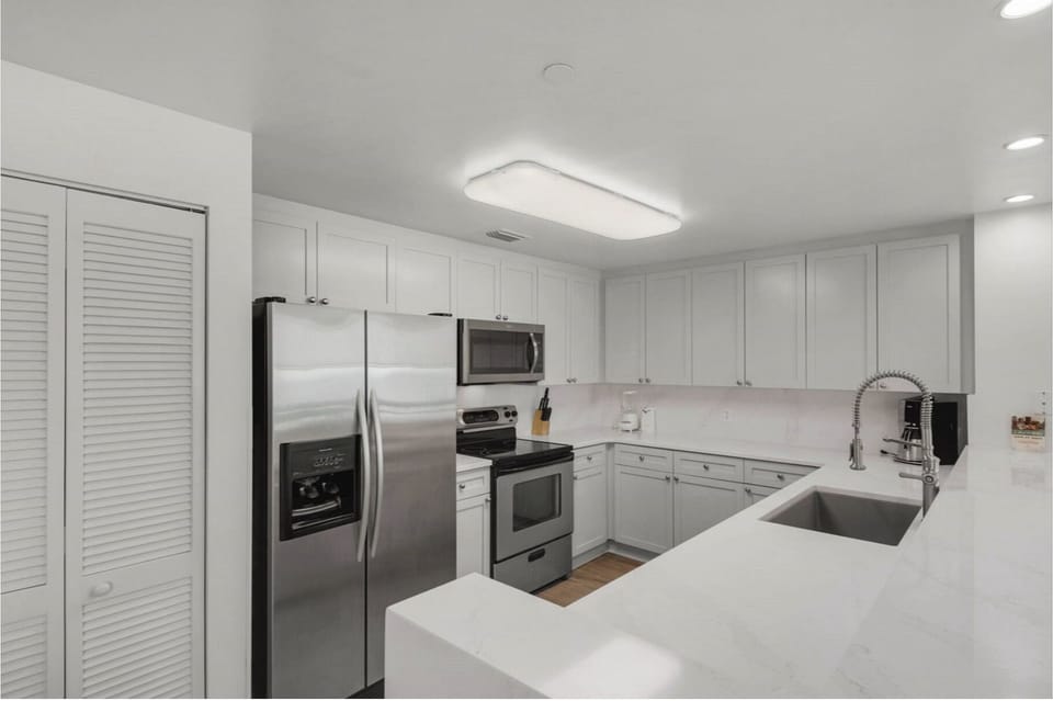 Your sleek modern kitchen features stainless steel appliances and pristine white countertops, perfect for preparing memorable meals during your stay.