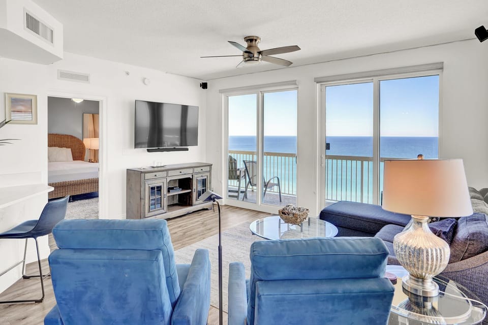 Relax in your bright living room where turquoise waters stretch endlessly beyond floor-to-ceiling windows, creating the perfect oceanfront retreat.