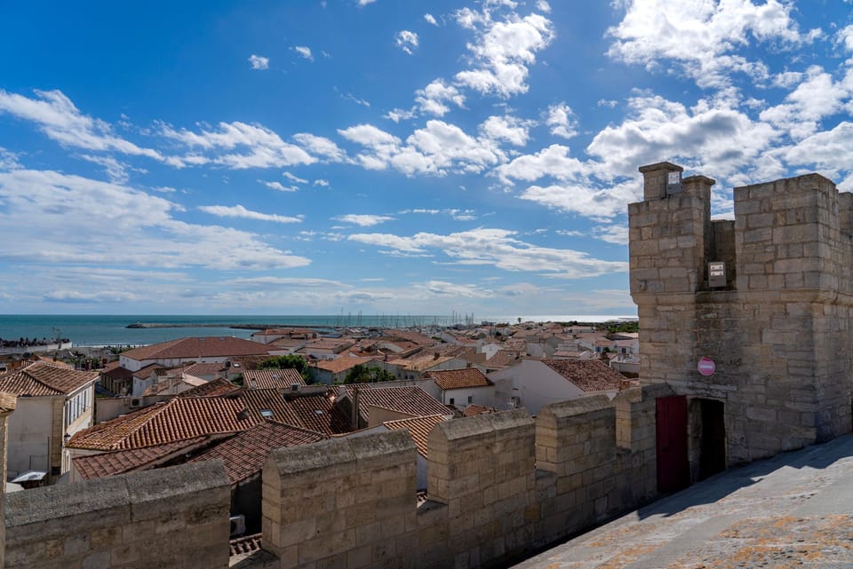 Terracotta rooftops and the historic ramparts of Aigues-Mortes stretch towards the harbour and open sea beyond.