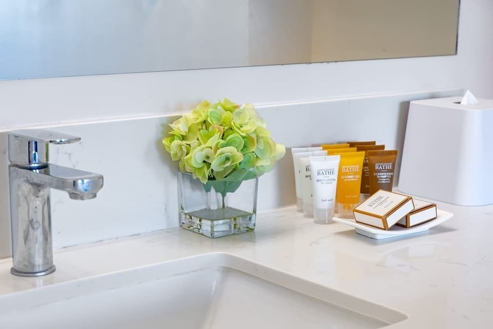 Modern bathroom countertop with complimentary toiletries and fresh floral arrangement.
