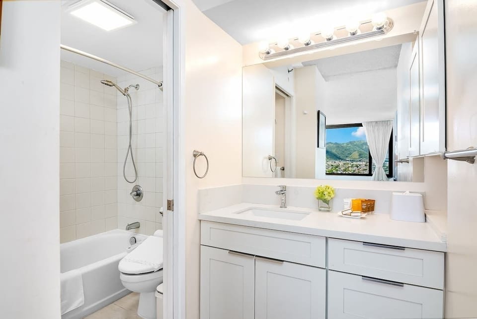 Bright bathroom with a large mirror and a view of the mountains through the window.