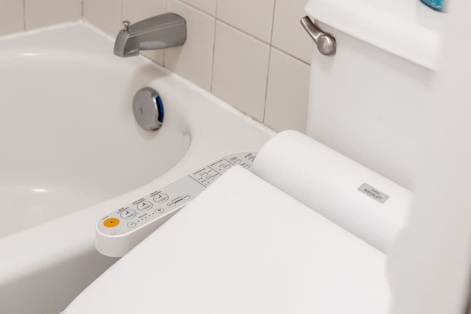 Modern bathroom featuring a high-tech bidet toilet seat next to a clean bathtub.