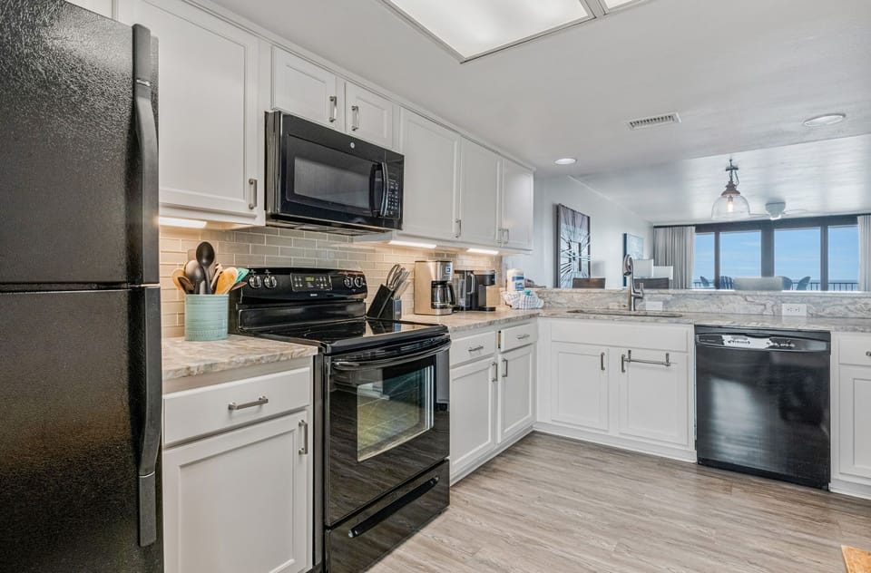 Fully equipped kitchen with white cabinets and breakfast bar at Wind Drift 209 SW