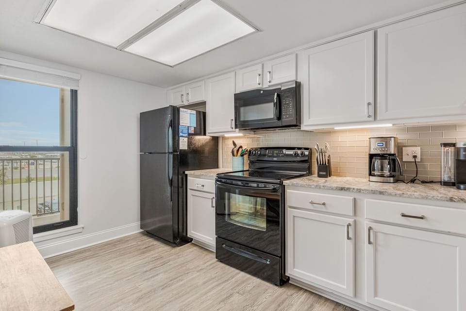 Fully equipped kitchen with white cabinets and breakfast bar at Wind Drift 209 SW