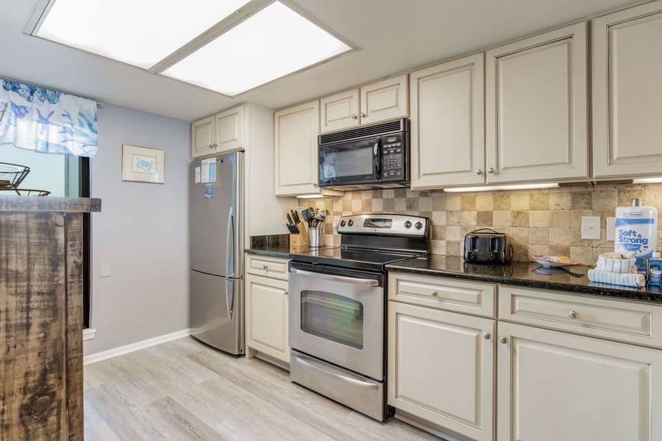 Kitchen with modern appliances and breakfast bar at Wind Drift Orange Beach