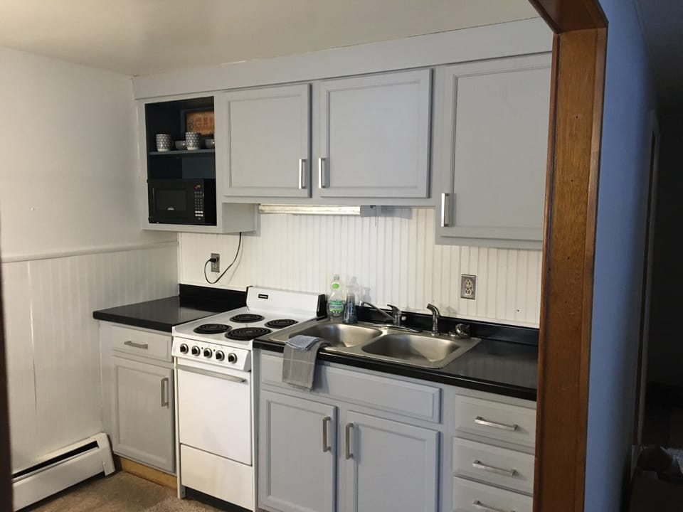 fully stocked kitchen, with a microwave, fridge, oven, coffee pot.