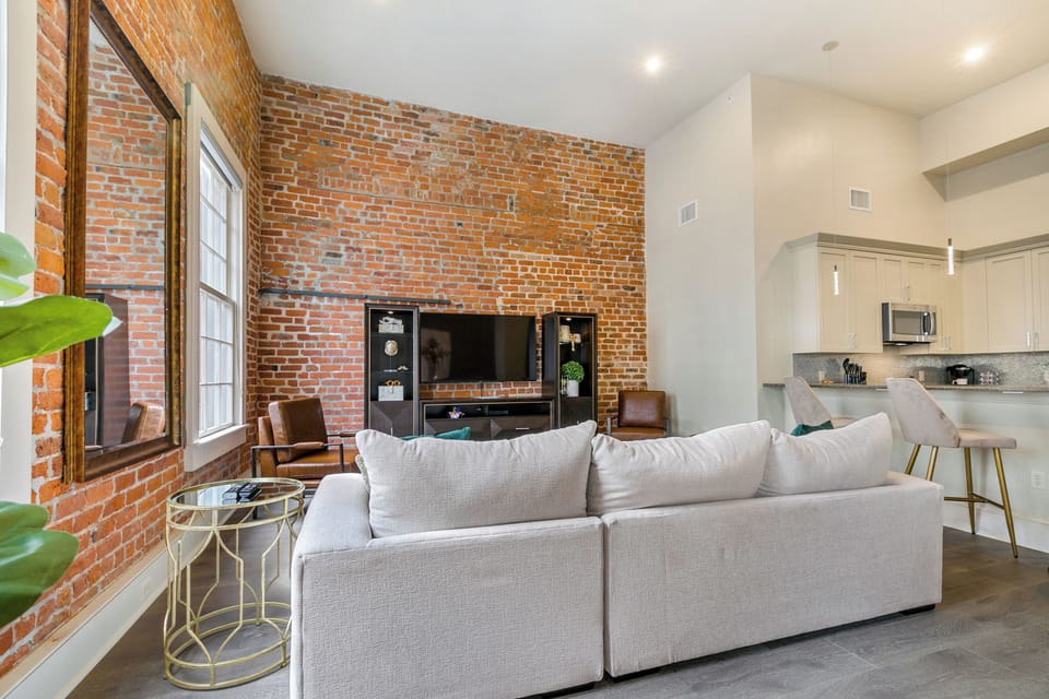 Open-concept living, kitchen, and dining area with ample seating. Relax on a large sectional and enjoy a 65” Samsung Smart 4K TV with streaming and DIRECTV Entertainment. Dining table seats six, plus bar seating for four. Plenty of natural light!