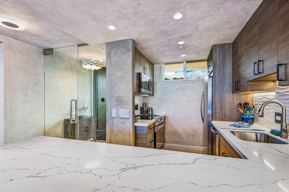 Cooking area with counter-depth fridge for more space. Quartz countertops.