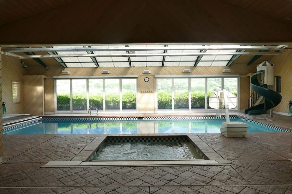 Jacuzzi spa and huge pool showing slide, diving board and water sports hoop. Also has multi colored led lights and sound.  Off to side shows the 2nd Kitchen and dining area and water toys galore