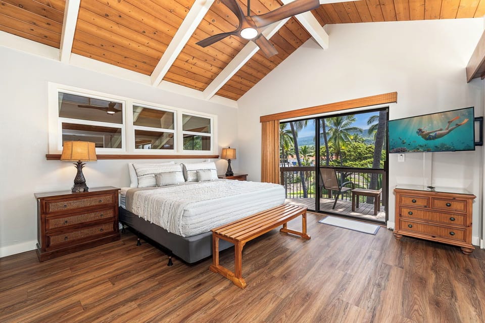 The primary suite rises under vaulted wood beams, its own lanai just off the room.