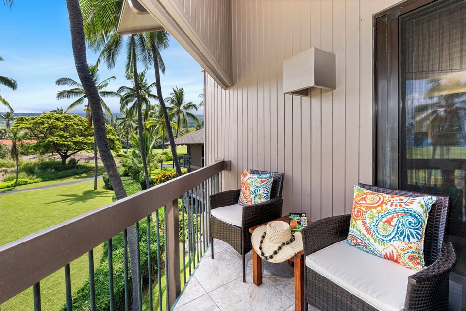 A quiet corner lanai with two chairs and a view into the palms.