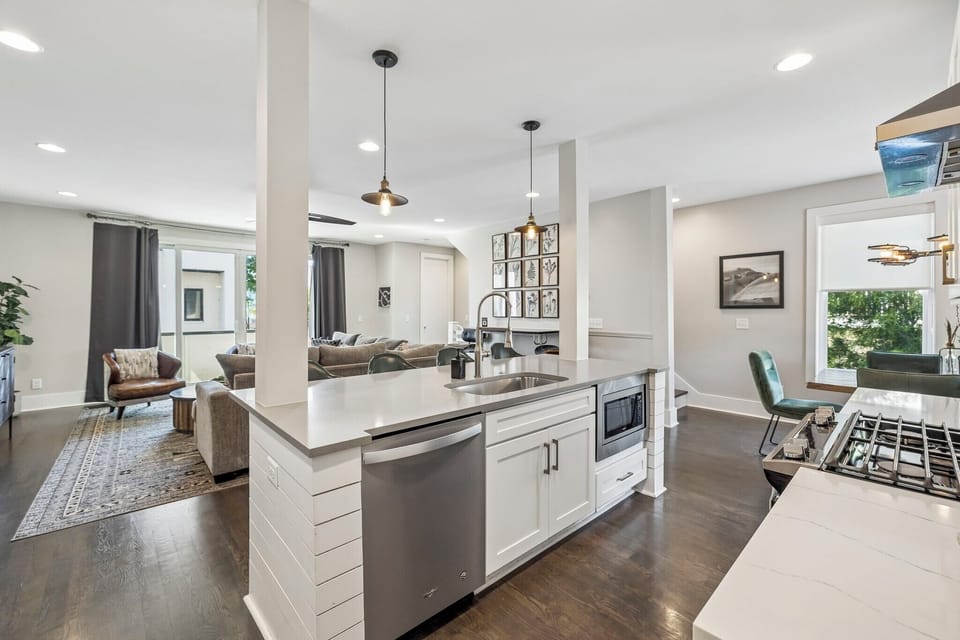 Spacious kitchen fully equipped with all the cooking essentials you need - Modern pendant lights and wood accents add warmth to this inviting culinary space - Whip up a feast or pour a drink, the open layout makes it easy to stay connected