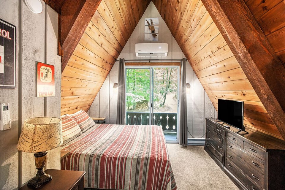 Loft bedroom with queen bed, smart TV and views of the woods