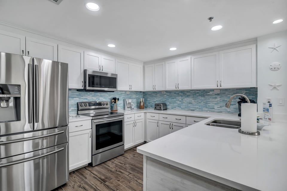 This fully functional kitchen boasts stainless steel appliances, sleek countertops, a decorative backsplash, and ample cabinet storage, ideal for everyday cooking and entertaining.