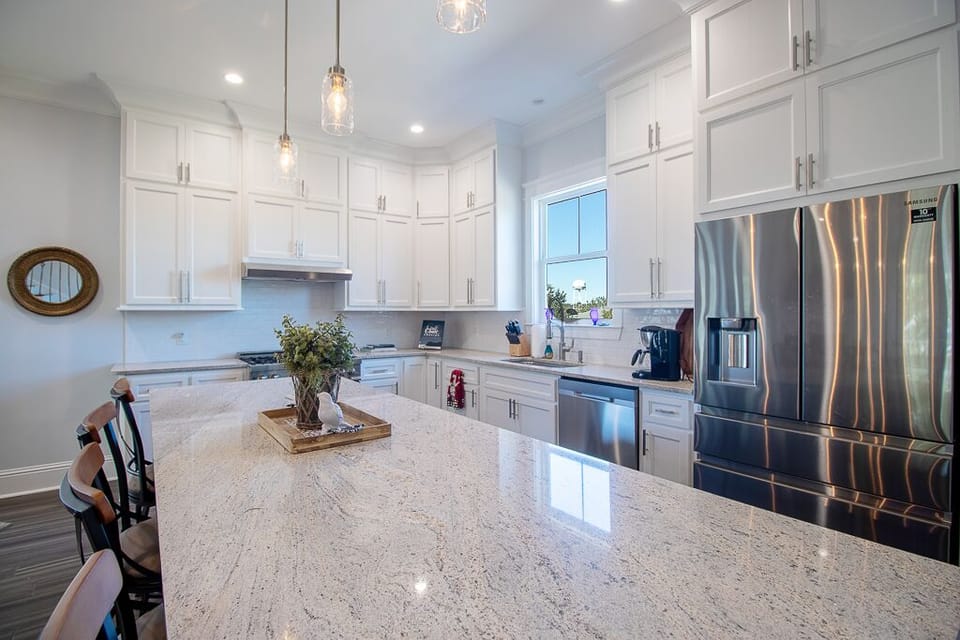 Island view towards professional gas cook top & modern 4 door refrigerator
