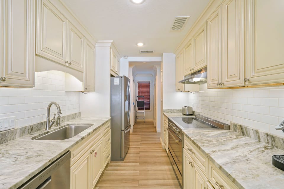 Start your morning in this bright coastal kitchen, brewing coffee as sunlight spills across marble countertops and plans for another perfect beach day begin.