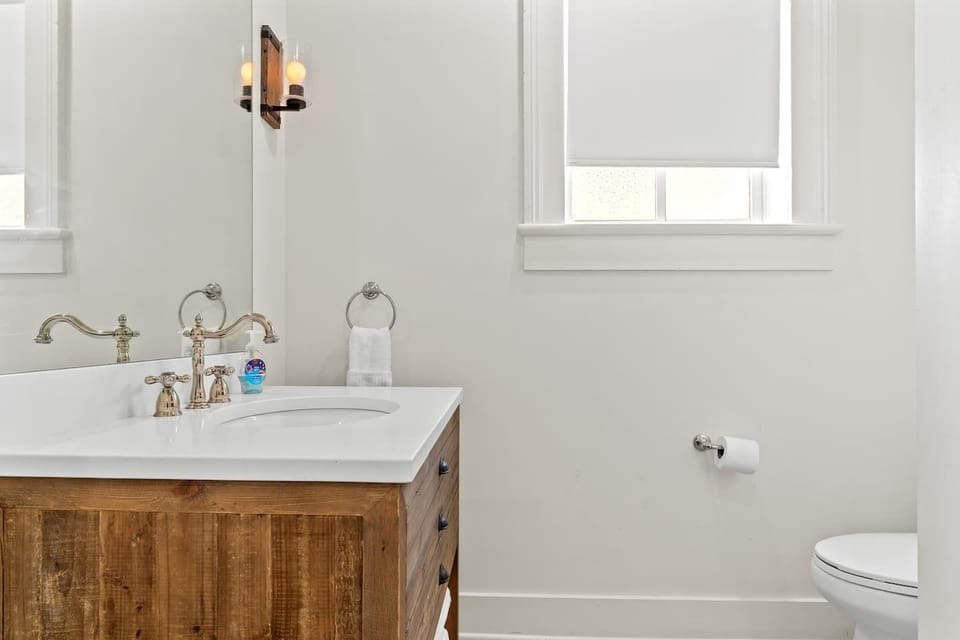 First bathroom vanity w/ sink & large mirror.
