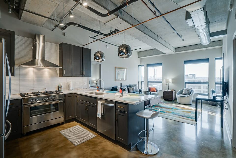 Sleek industrial loft with fully equipped kitchen, stainless appliances, and city views from your living space.