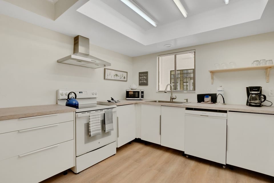 Full kitchen features modern appliances - a 2 door fridge, coffee maker, stove, oven, kettle, toaster, microwave, dishwasher, basic cooking utensils, and dishware, cutleries, and glasses.
