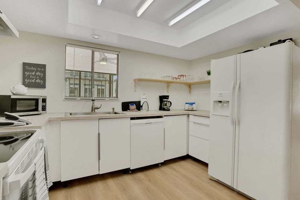 Full kitchen features modern appliances - a 2 door fridge, coffee maker, stove, oven, kettle, toaster, microwave, dishwasher, basic cooking utensils, and dishware, cutleries, and glasses.