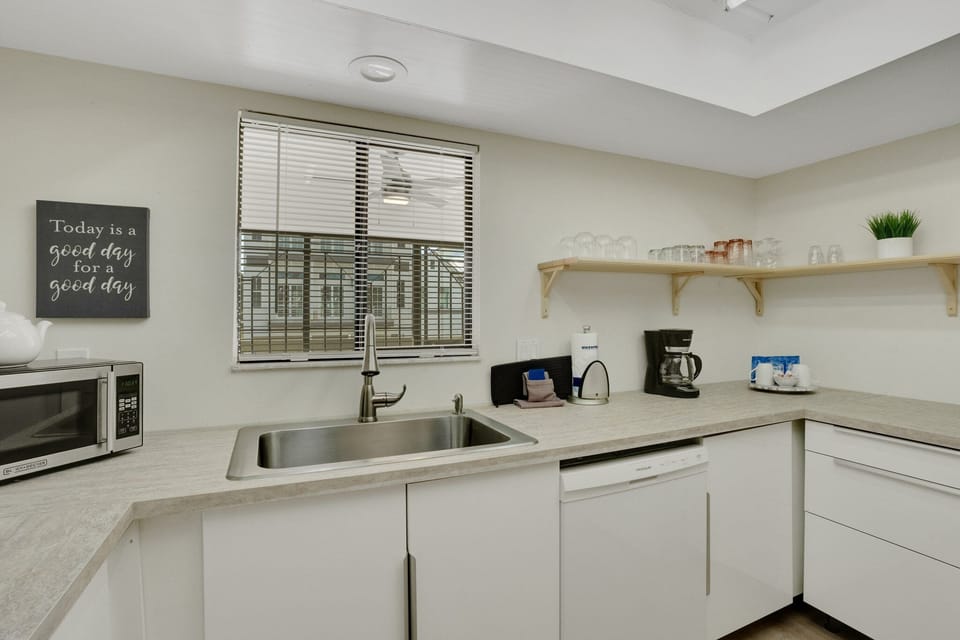 Full kitchen features modern appliances - a 2 door fridge, coffee maker, stove, oven, kettle, toaster, microwave, dishwasher, basic cooking utensils, and dishware, cutleries, and glasses.