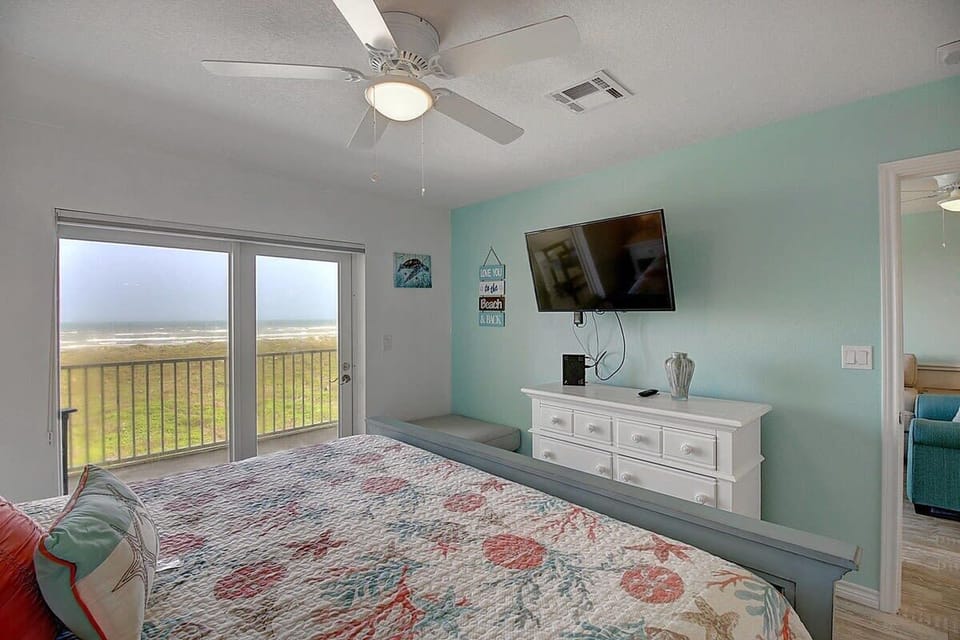 Master Bedroom — King Bed, Coral Reef Bedding, White Dresser, TV & Ocean Balcony View