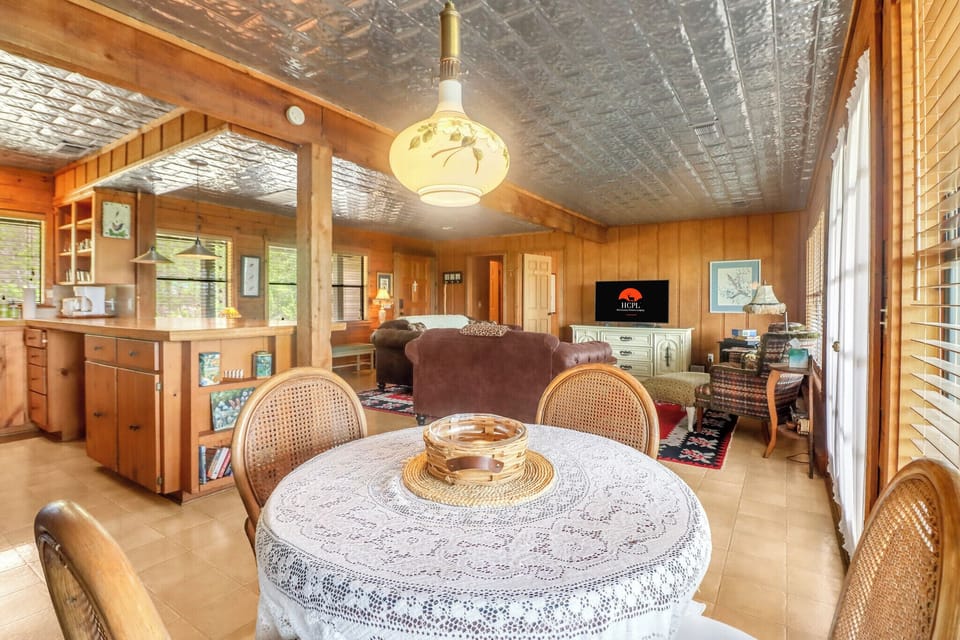 Relax in this charming open-concept living space with warm wood paneling, vintage tin ceiling, and cozy furnishings—perfect for gathering after a day of adventure.