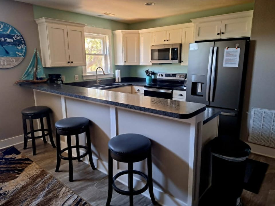 Kitchen area with padded barstools. All new appliances for 2026.