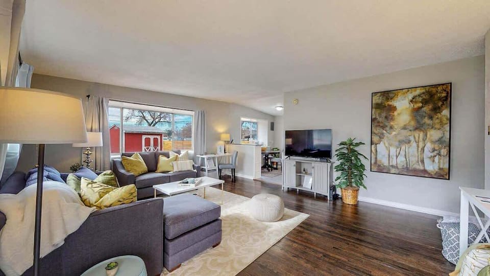 Stylish and cozy living area with a plush sectional, warm lighting, and modern decor. The open layout connects seamlessly to the kitchen, creating a welcoming space for relaxation and entertainment.