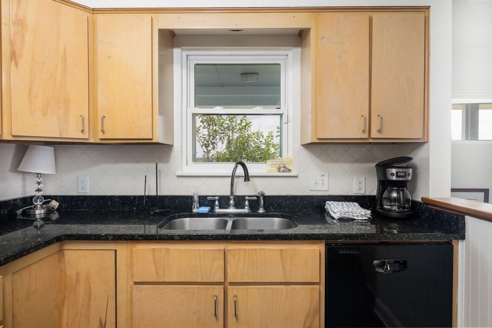 The kitchen features black granite countertops and a coffee maker