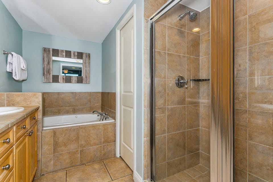 Unwind after your day with both a soaking tub and a refreshing walk-in shower—your choice of relaxation awaits in this soothing, tile-lined bathroom.