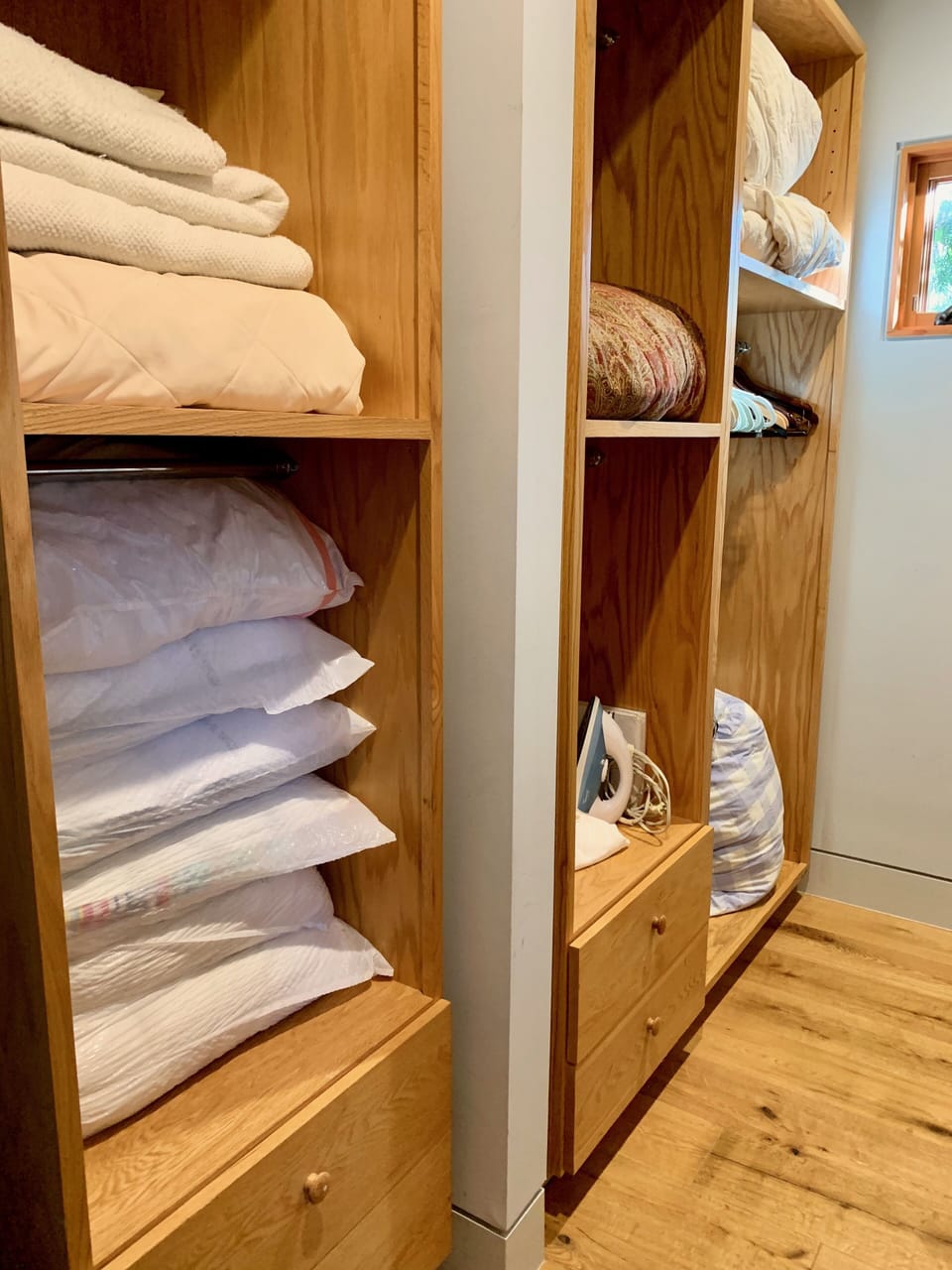 Walk-in closet with extra pillows, blankets, clothes hanging rack and dressers.