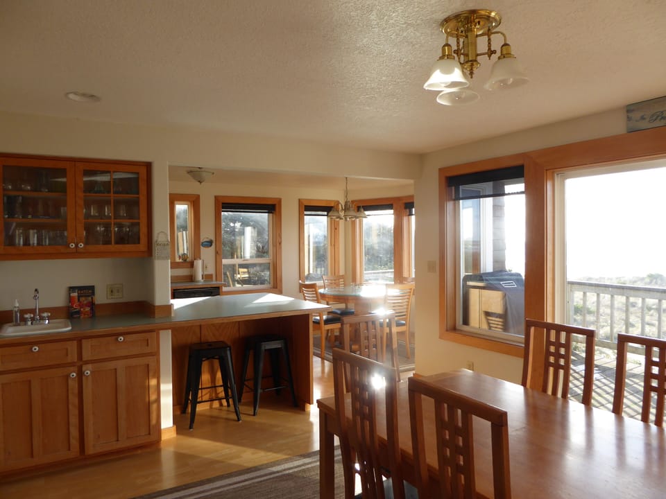 View from dining area with wet bar into bright, ocean view kitchen dining.