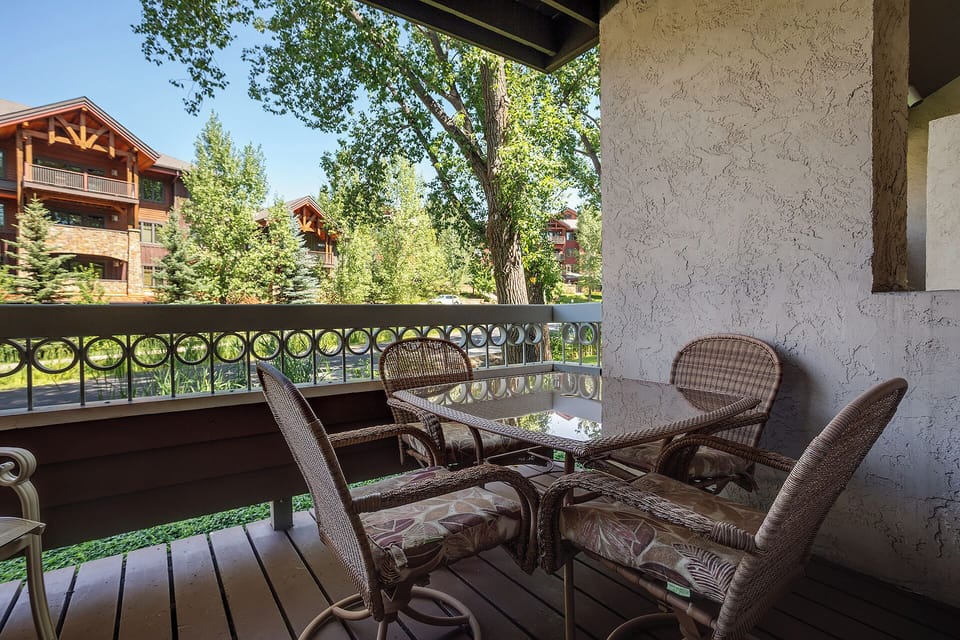 Your private balcony offers peaceful moments with wicker seating overlooking lush trees and charming neighborhood architecture.