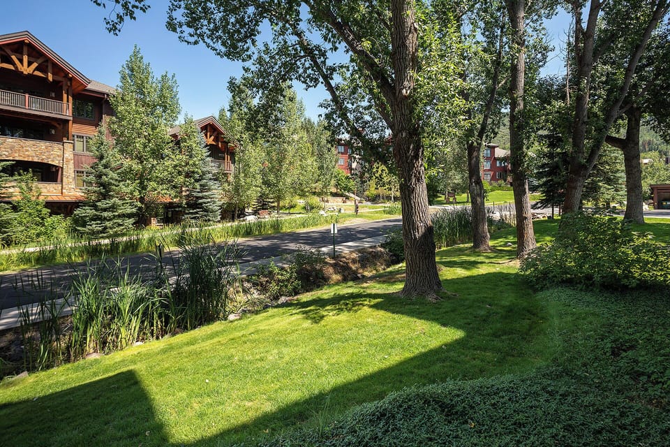 Peaceful resort grounds feature lush landscaping, mature trees, and walking paths connecting multi-story lodge buildings in a serene mountain setting.