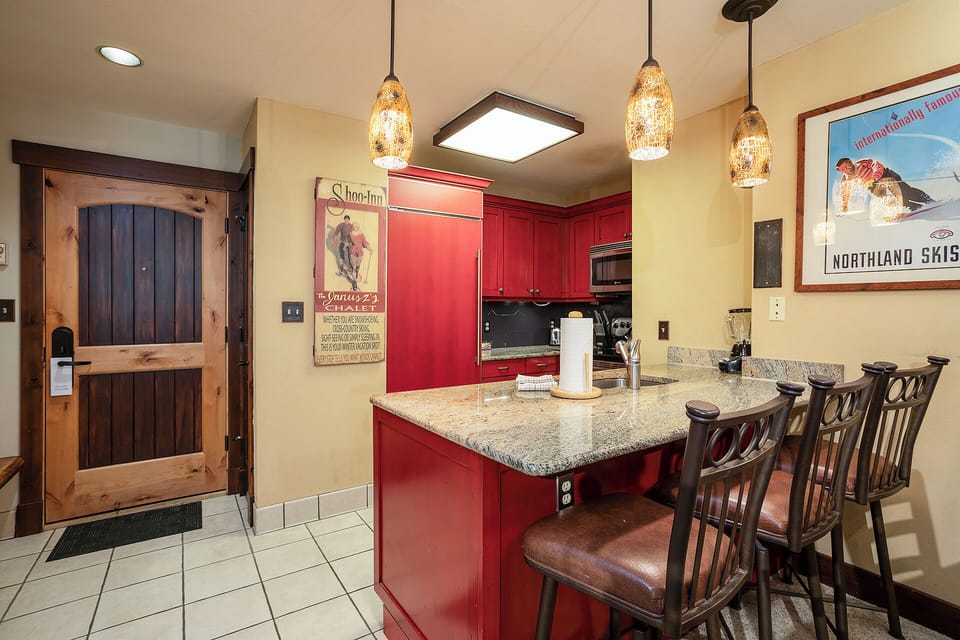 Cook your favorite meals in this welcoming kitchen with granite countertops, red cabinets, and elegant pendant lighting.