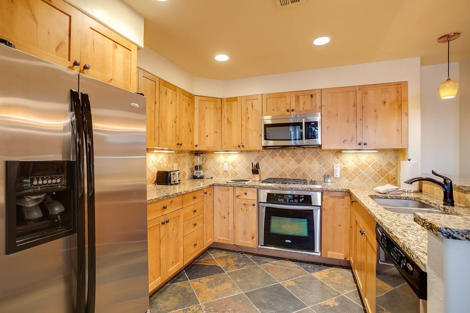 Your fully equipped kitchen features granite countertops, stainless steel appliances, and warm wood cabinetry—perfect for preparing meals during your stay.