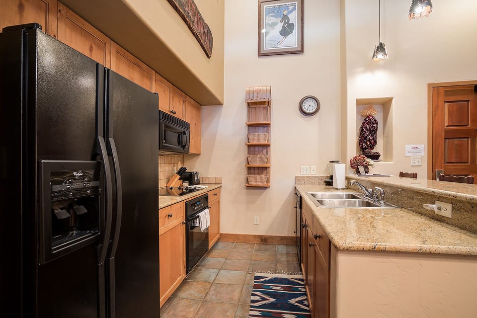 Your fully equipped kitchen features granite countertops, modern appliances, and warm wood cabinets - perfect for preparing meals during your stay.