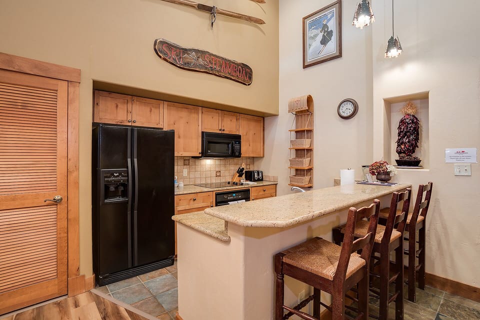 Your fully equipped kitchen features warm wood cabinets, granite counters, and a breakfast bar perfect for morning coffee or casual meals.
