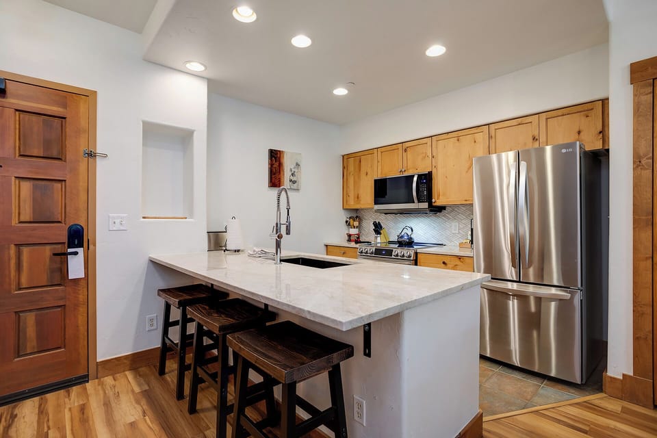Your fully equipped kitchen invites culinary adventures with gleaming countertops, modern appliances, and cozy breakfast bar seating for morning coffee moments.