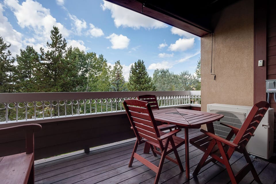 Savor morning coffee on your private balcony overlooking peaceful treetops, where wooden furniture invites relaxation.