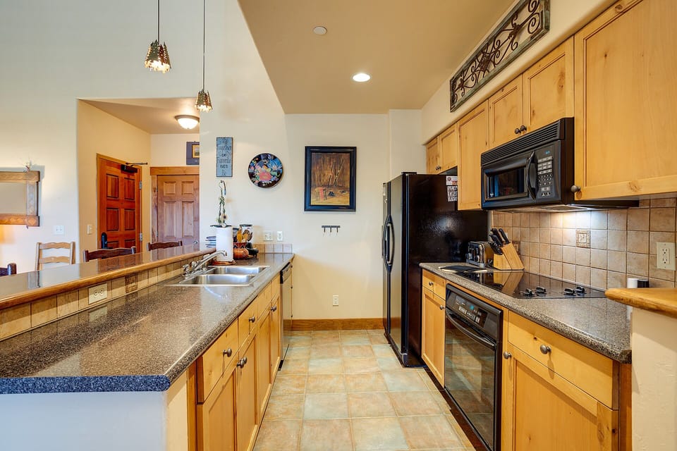 Step into your fully equipped kitchen featuring warm wood cabinets, granite counters, and stainless steel appliances perfect for preparing memorable meals.